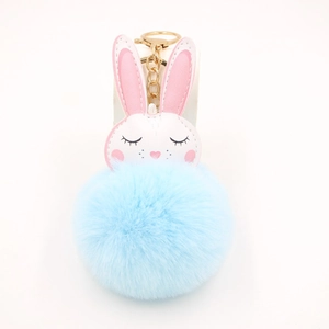 Vista dettagliata del morbido pompon di peluche azzurro e della catena dorata ad anello