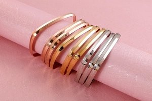 Close-up of geometric titanium steel bangles in gold, rose gold and silver finishes