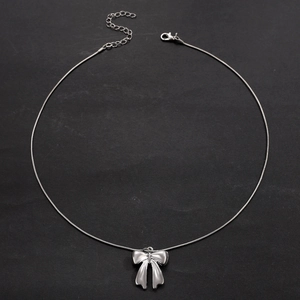 Detail of silver bow pendant necklace with adjustable lobster clasp on dark background