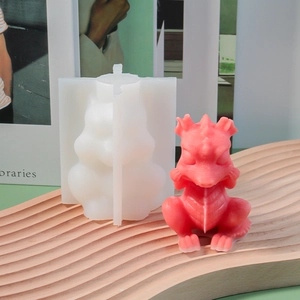 Detailed dragon silicone mold with red wax figurine on a wavy wooden tray for DIY crafts