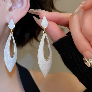 Close-up of elegant leaf-shaped drop earrings with white drip oil and gold metal accents