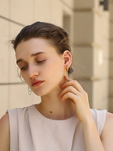 Close-up of asymmetric 18K gold-plated earrings with chain tassels and zircon stones