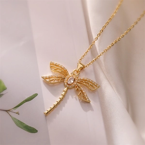 Macro detail of golden dragonfly pendant necklace with crystal wings and oval gemstone