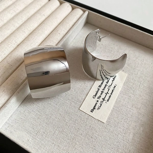 Close-up of polished silver wide C-shape hoop earrings in a jewelry gift box
