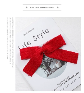 Close-up of a festive red plush ribbon bow on a magazine for Christmas tree decoration