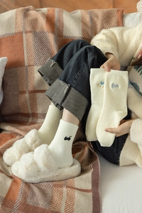 Detail showing plush cream socks with cat embroidery and matching fleece slippers
