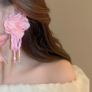 Detailed view of pink mesh petal earrings with cascading bead tassels on model