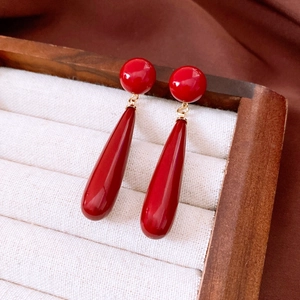 Detail shot of vintage red teardrop earrings with golden accents in a wooden jewelry box