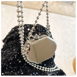 Macro shot of silver octagonal mini metal bag with a polished mirror finish on black sequins