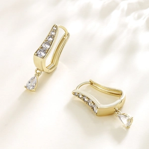 Elegant gold U-shaped hoop earrings with teardrop zircon drop on white satin background