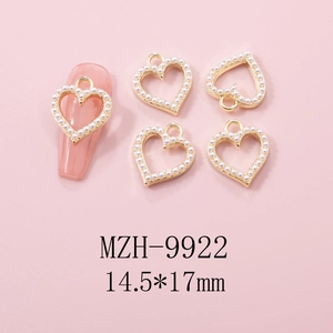 Golden heart nail charm with white pearls and pink manicure application detail