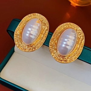 Macro detail of gold textured oval earring featuring a large white irregular pearl inlay