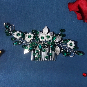 Detailed view of silver hair comb with green crystals, white pearls and leaf motifs