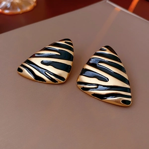 Macro shot of vintage triangle stud earrings with gold and black zebra pattern textures