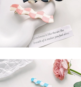 Close-up of wavy checkerboard hair clips in pink, blue, and black pastel tones