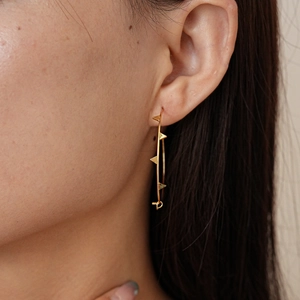 Detail of a gold spike hoop earring shown on a model for a stylish punk look