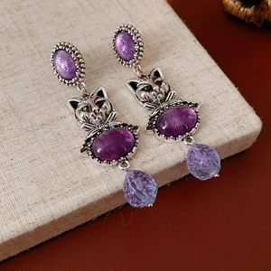 Detail view of vintage cat-shaped earrings with purple stones and antique silver finish