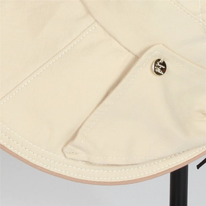 Detailed macro view of beige sun hat fabric texture with golden logo emblem and stitching