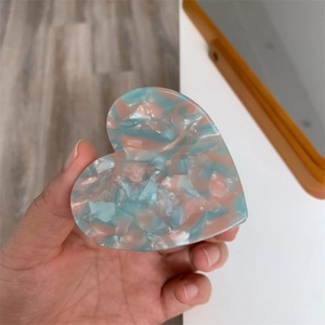Close-up of pink and blue marble pattern heart-shaped hair claw made of premium acetate
