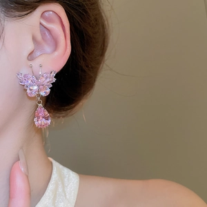 Detail of pink zircon butterfly earrings with teardrop pendants on model's ear