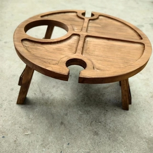 Detail of wooden folding picnic table featuring slots for wine bottles and wine glasses