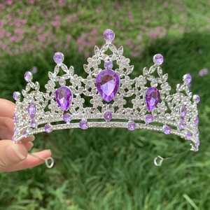 Detail of hand holding silver bridal crown with purple crystals and sparkling rhinestones