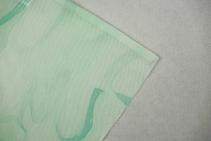 Detailed close-up of mint green breathable mesh fabric with dark green wave print