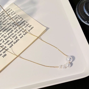Close-up of golden pearl necklace with elegant wheat ear design on a white tray