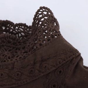 Detailed view of dark brown crewneck top featuring crochet lace trim and embroidery texture