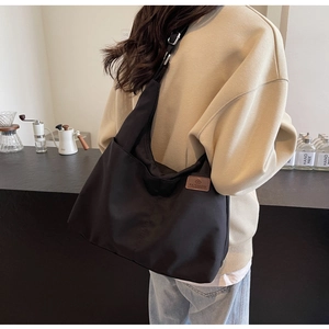 Practical large black canvas tote bag shown on model in a stylish coffee shop setting