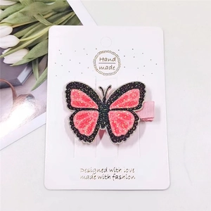 Detail showing a pink and black sequined butterfly hair clip on a display card