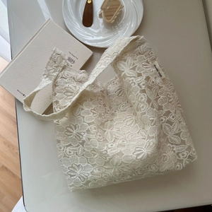 Detailed close-up of white lace floral embroidery and 'simple wish' label on a cotton tote