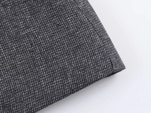 Macro del tessuto tweed grigio scuro che mostra la trama dettagliata della fibra del blazer