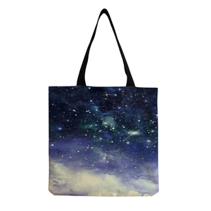 Dettaglio della vivace stampa nebulosa stellata e dei manici neri su una borsa tote