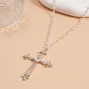Detailed macro of silver cross pendant with baroque fleur-de-lis and pearl beaded chain