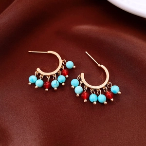 Detail of 14K gold plated earrings with agate and turquoise beads on silk fabric