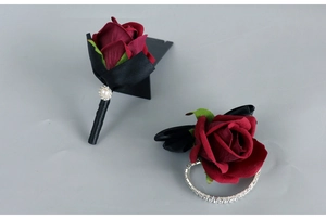 Detail of burgundy artificial rose boutonniere and wrist corsage with black ribbons