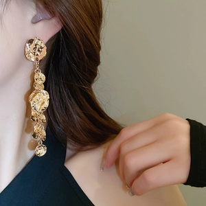 Vue détaillée de longues boucles d'oreilles dorées à pampilles avec texture martelée
