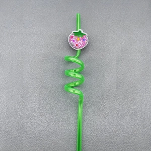 Detail view of green spiral reusable straw with sequin-filled strawberry ornament