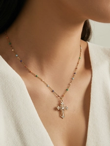 Close-up of model wearing a gold cross necklace with multicolored beads and rhinestones