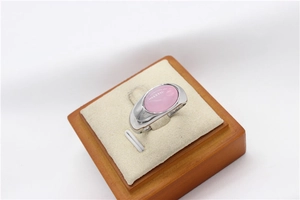 Close-up of a silver ring with an oval pink cat-eye stone on a beige display stand