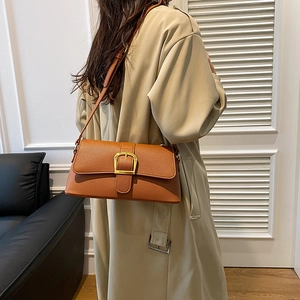 Brown leather baguette bag with gold buckle detail worn with a beige trench coat