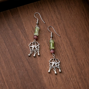 Detailed macro of vintage silver hollow flower and green bamboo beads tassel earring