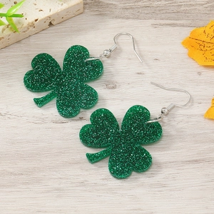Detailansicht grüner Glitzer-Kleeblatt-Ohrringe auf rustikalem Holz für St. Patrick's Day