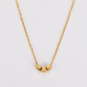 Macro detail of golden O-chain necklace featuring three small cube pendant beads