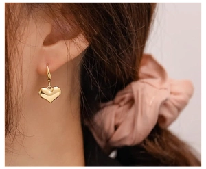 Close-up of elegant gold heart-shaped dangle earring worn for a chic vintage aesthetic