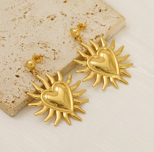 Detail of 18K gold heart earrings with sunburst edges on a minimalist stone background