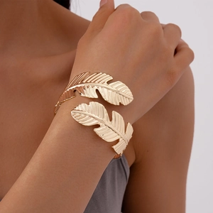Close-up of golden leaf-shaped open bracelet with detailed texture on model's wrist
