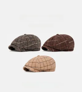 Detailed view of three herringbone and plaid newsboy caps in gray, brown, and beige wool