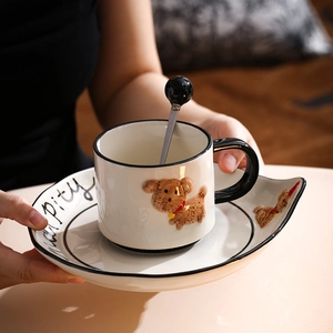 Close-up of hand-painted ceramic dog mug set with irregular saucer and mixing spoon